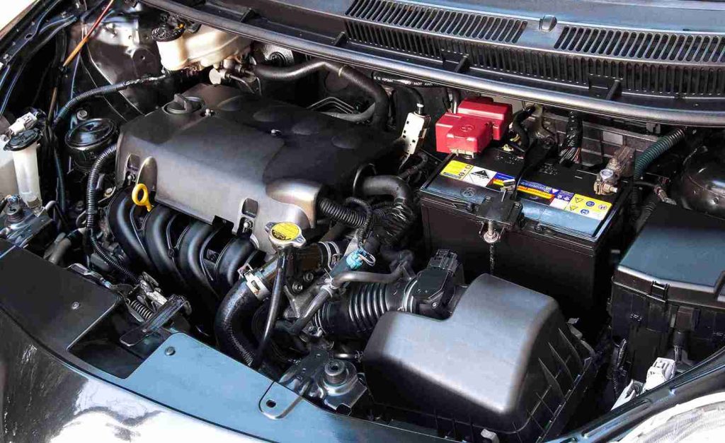 The hood of a car is open, displaying the engine and the car battery, emphasizing the vehicle's mechanical details.